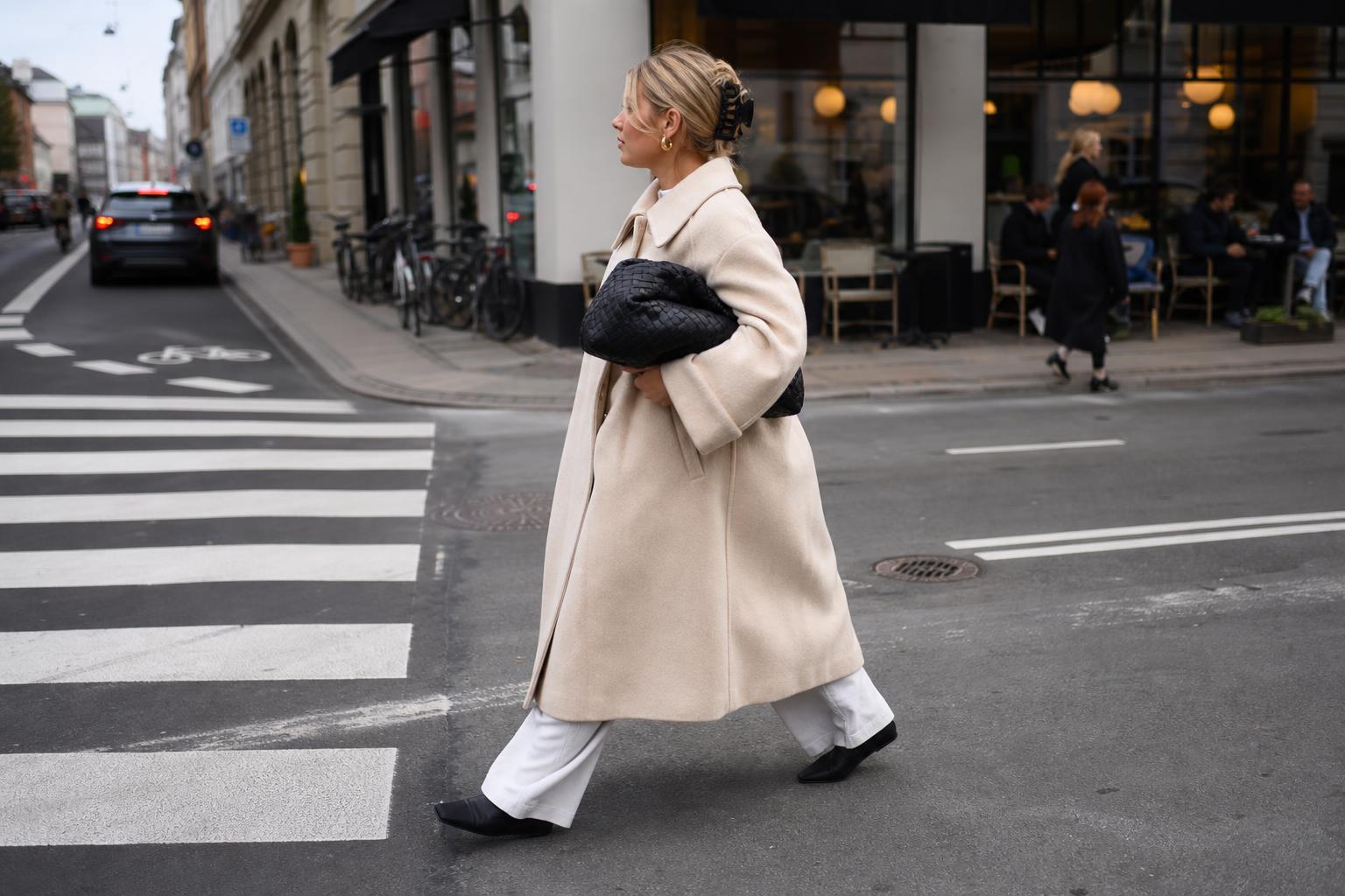 Copenhagen street style look with neutral oversized coat, straight denim, ballet flats, and a playful printed scarf on a city street