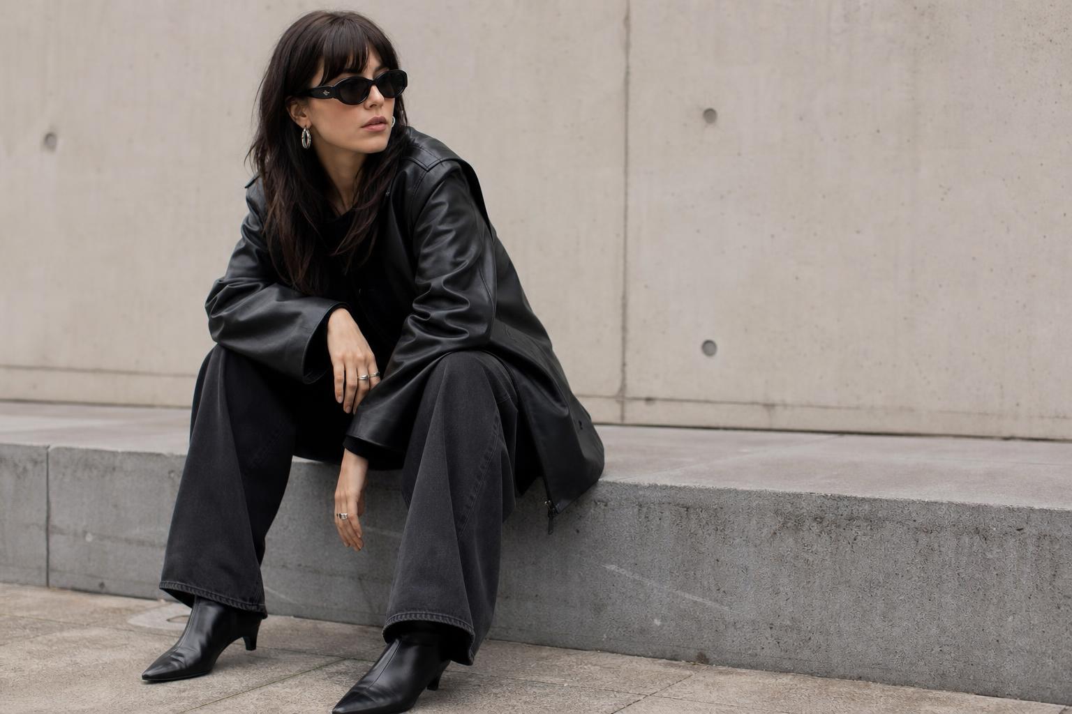Alt capsule wardrobe spring look with jumbo jeans, offbeat leather jacket, and graphic tee in a city street setting