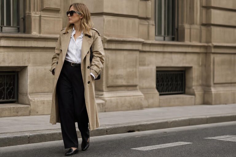 Timeless style inspiration outfit with beige trench coat, white shirt, black trousers and loafers in a city street