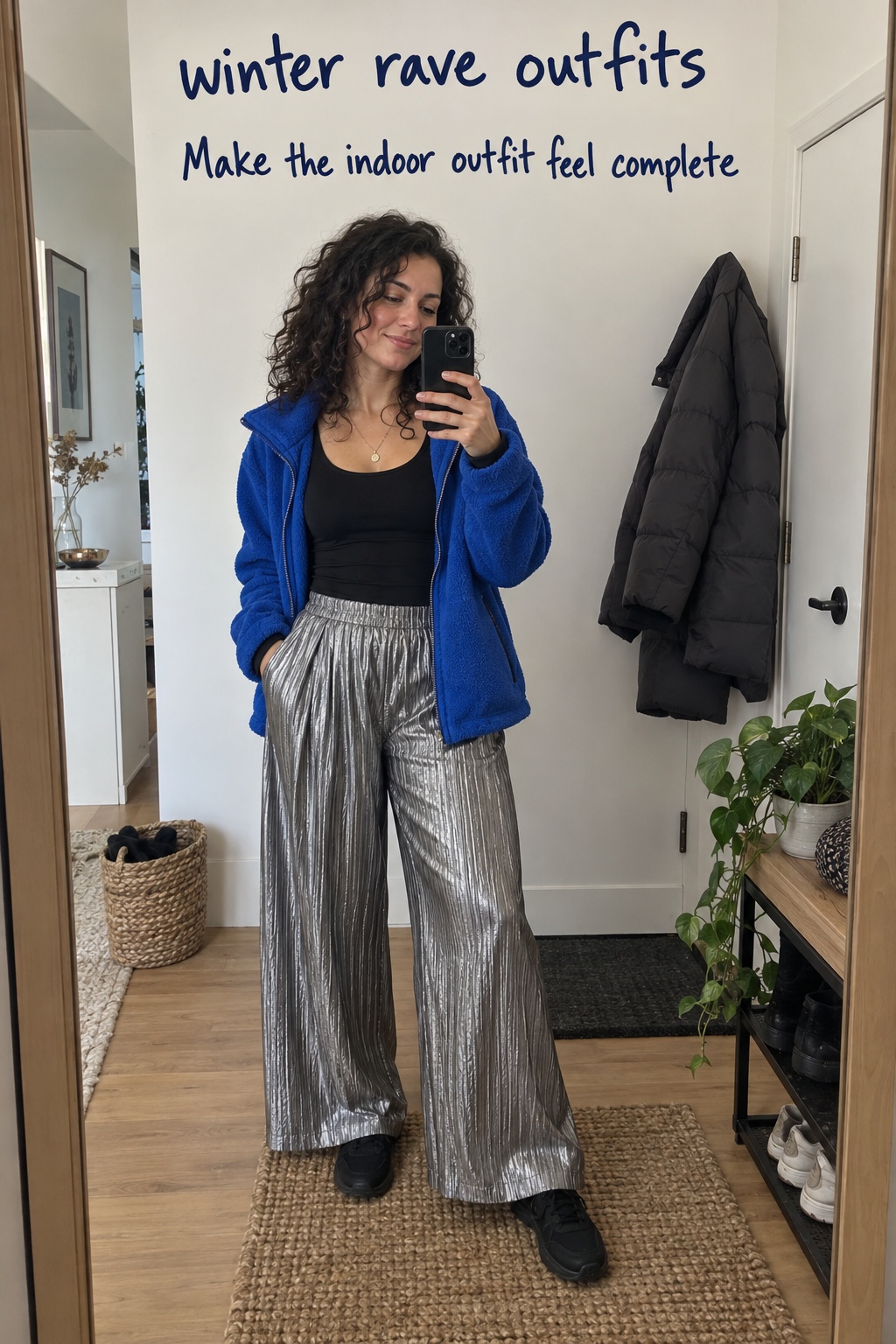 Winter rave outfits with silver pleated pants, black top, and blue fleece in a candid mirror scene